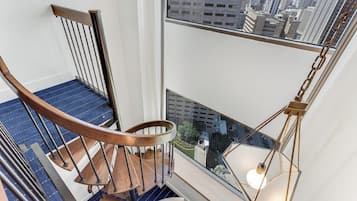 Una scala a chiocciola con gradini in legno e ringhiere in metallo, che conduce a un balcone con vista sulla città.