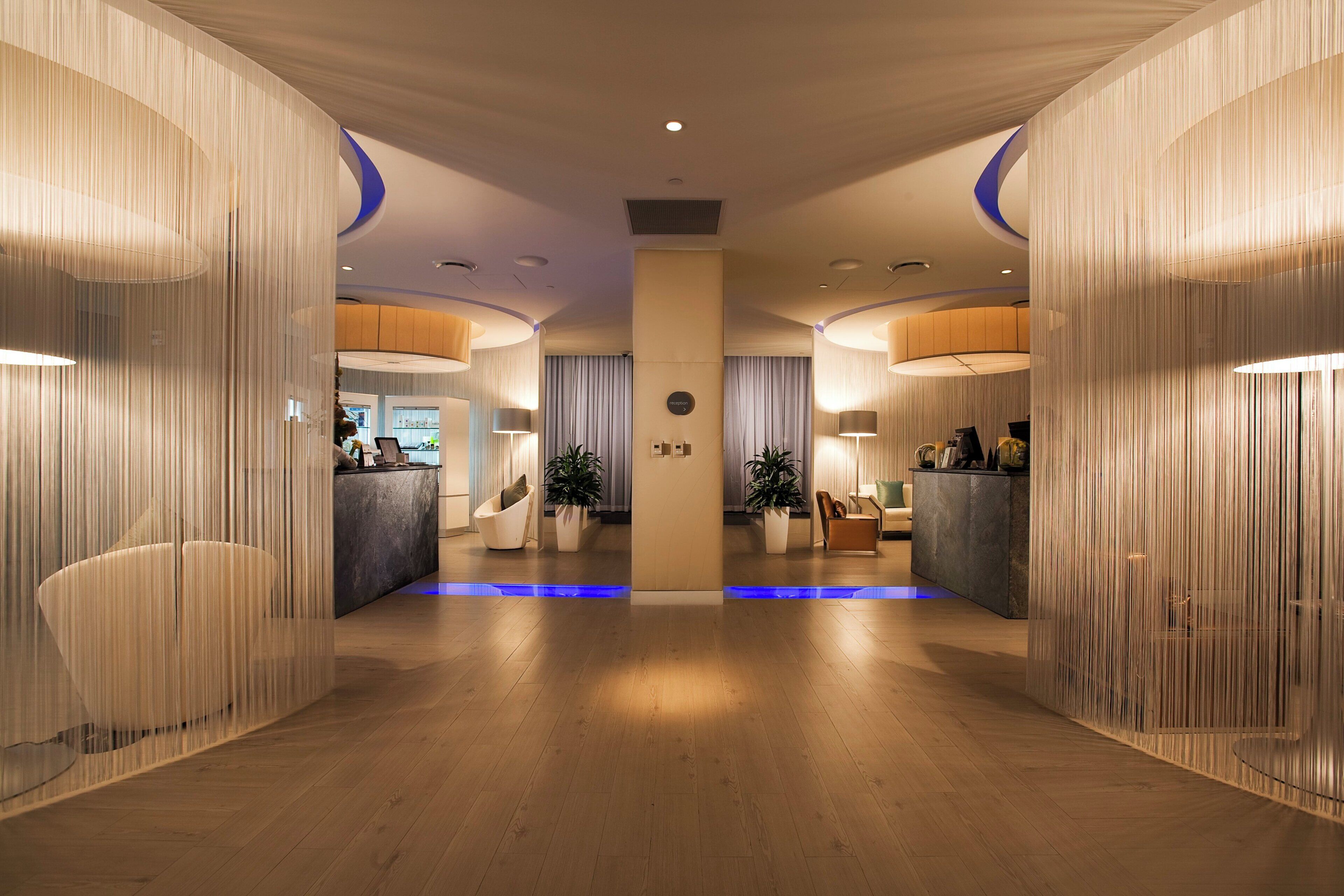 A hotel lobby with a reception desk, seating area, and a blue-lit pathway.