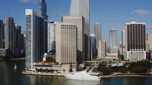 A waterfront cityscape with high-rise buildings, including a hotel with a large white facade and a marina with boats.