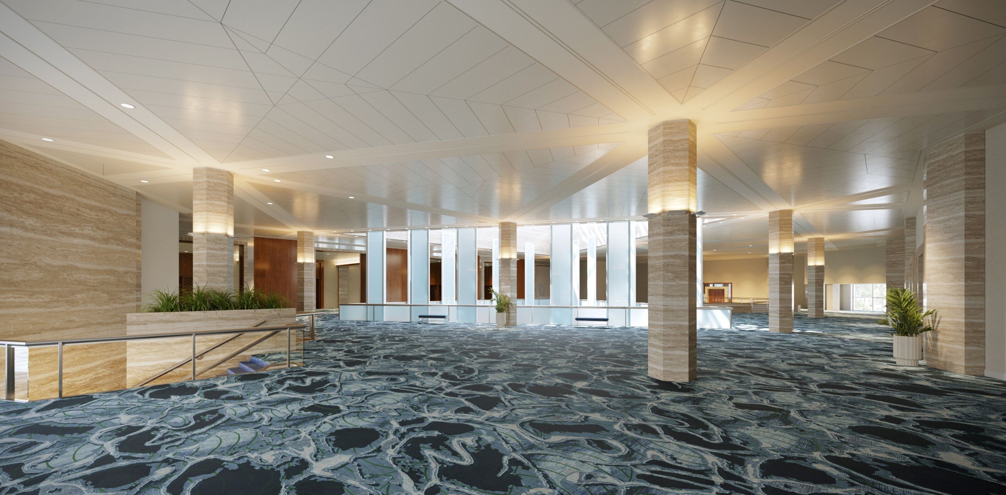 A spacious lobby with a patterned carpet, large pillars, and a high ceiling.