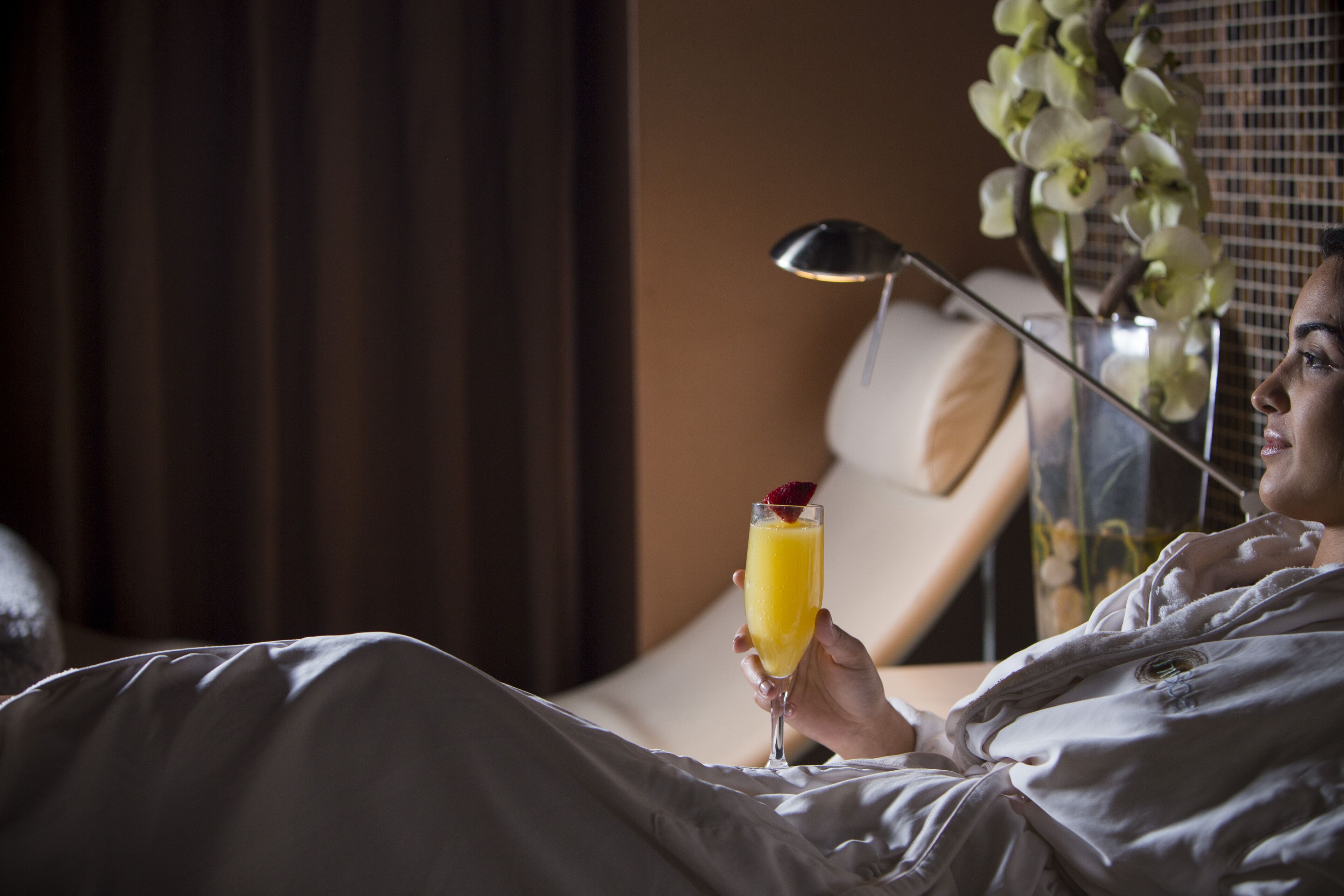 A person in a hotel room holding a drink.