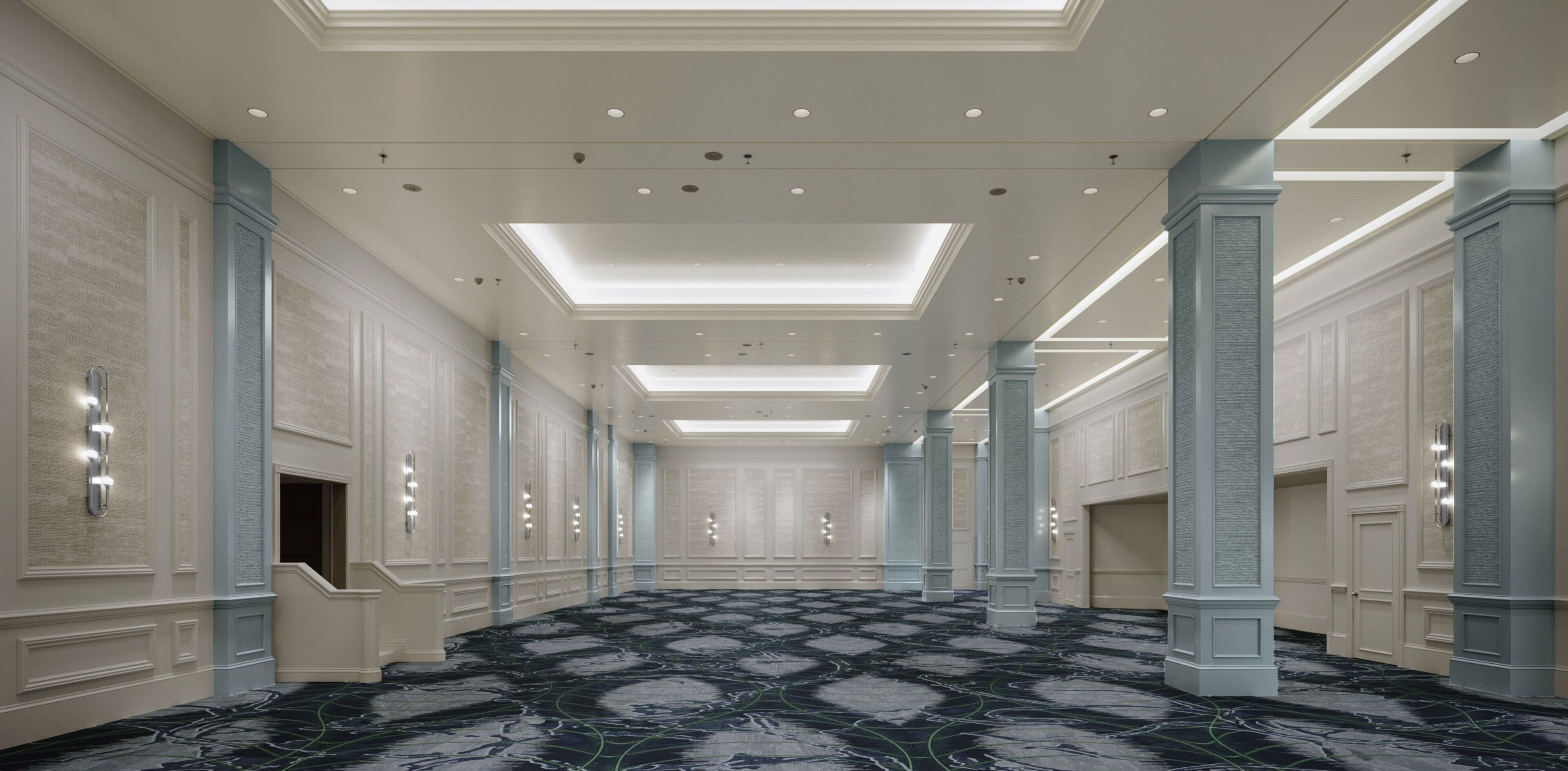 Un pasillo de hotel con piso de mármol, iluminación empotrada y columnas.