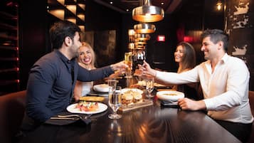 Un grupo de personas brindando con bebidas en una mesa con varios platos y vasos.