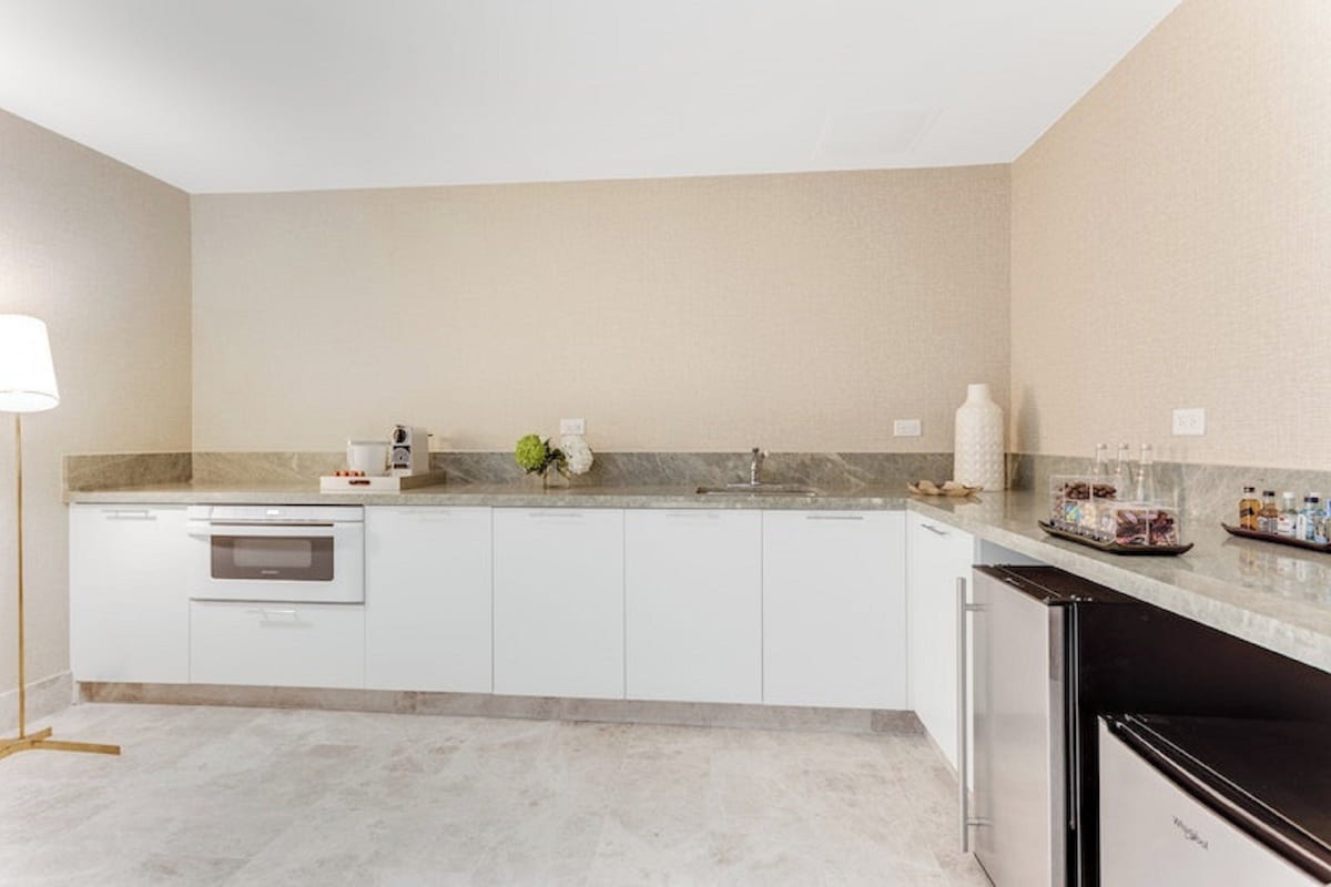 A modern kitchen with white cabinetry, a built-in oven, a sink, and a refrigerator.