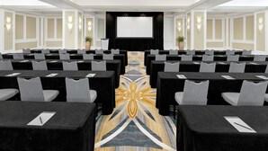A conference room with rows of tables and chairs, a large screen at the front, and a patterned carpet. - InterContinental Miami by IHG (Miami)