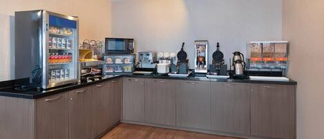 Una cocina moderna equipada con refrigerador, microondas, tostadora, máquina para gofres, cafetera y una máquina expendedora.