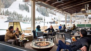 An outdoor seating area with a fire pit, tables, and chairs, overlooking a snowy mountain. - Park Hyatt Beaver Creek Resort and Spa (Avon)