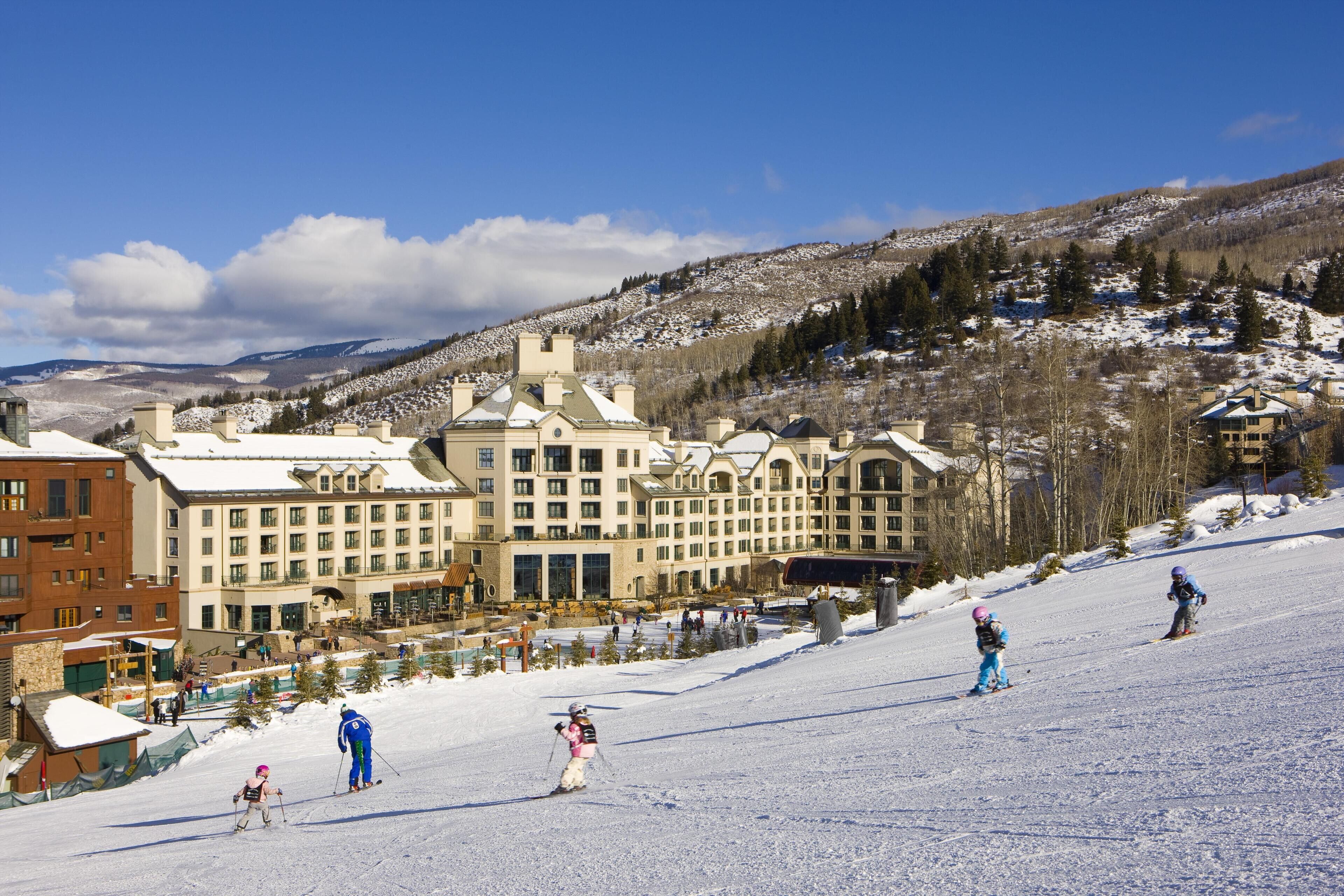 Une station de ski comprenant plusieurs bâtiments, dont un grand chalet doté d’un toit imposant et un bâtiment plus petit situé à gauche.
