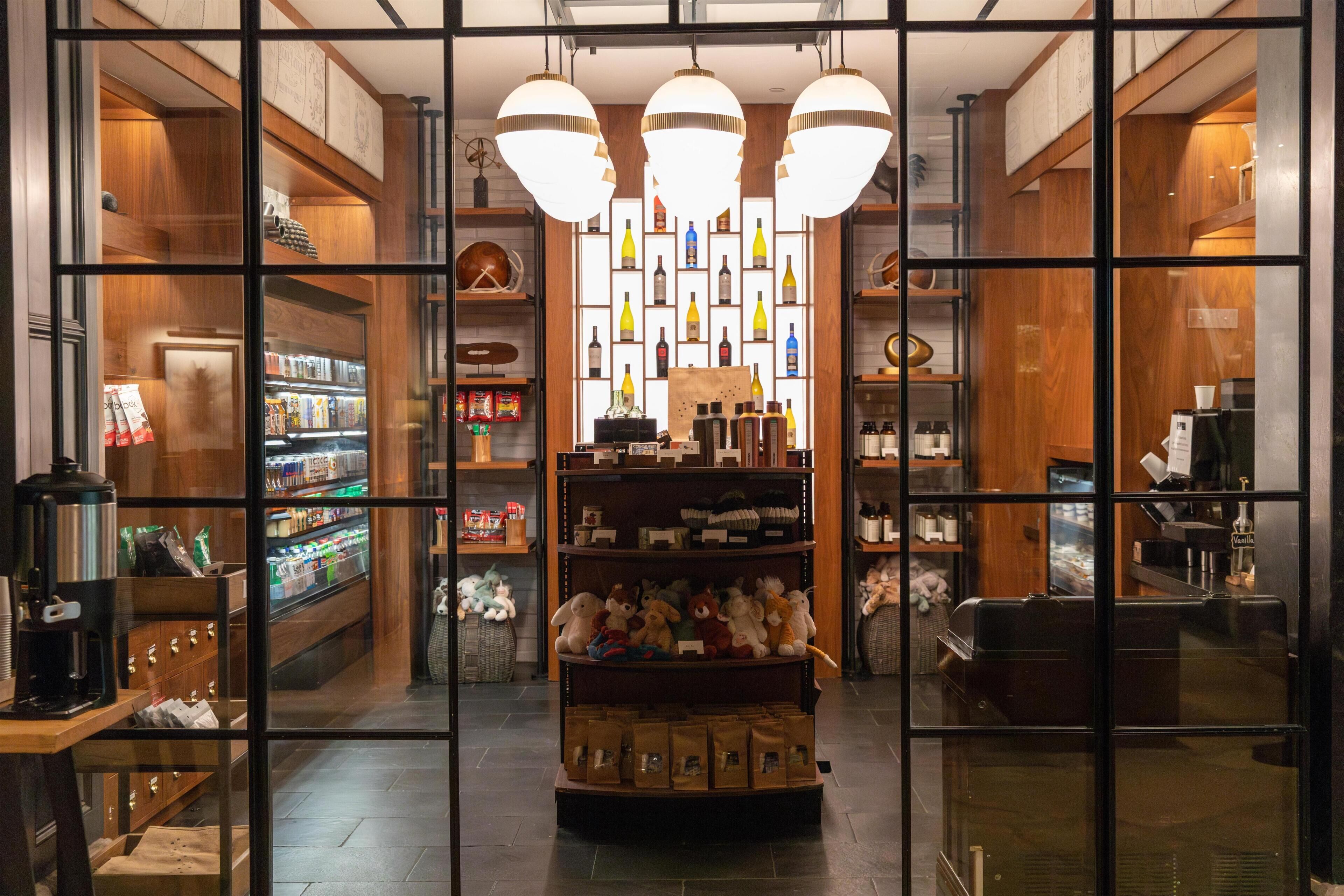 A hotel lobby with a central display of bottles, a coffee machine, and plush toys.