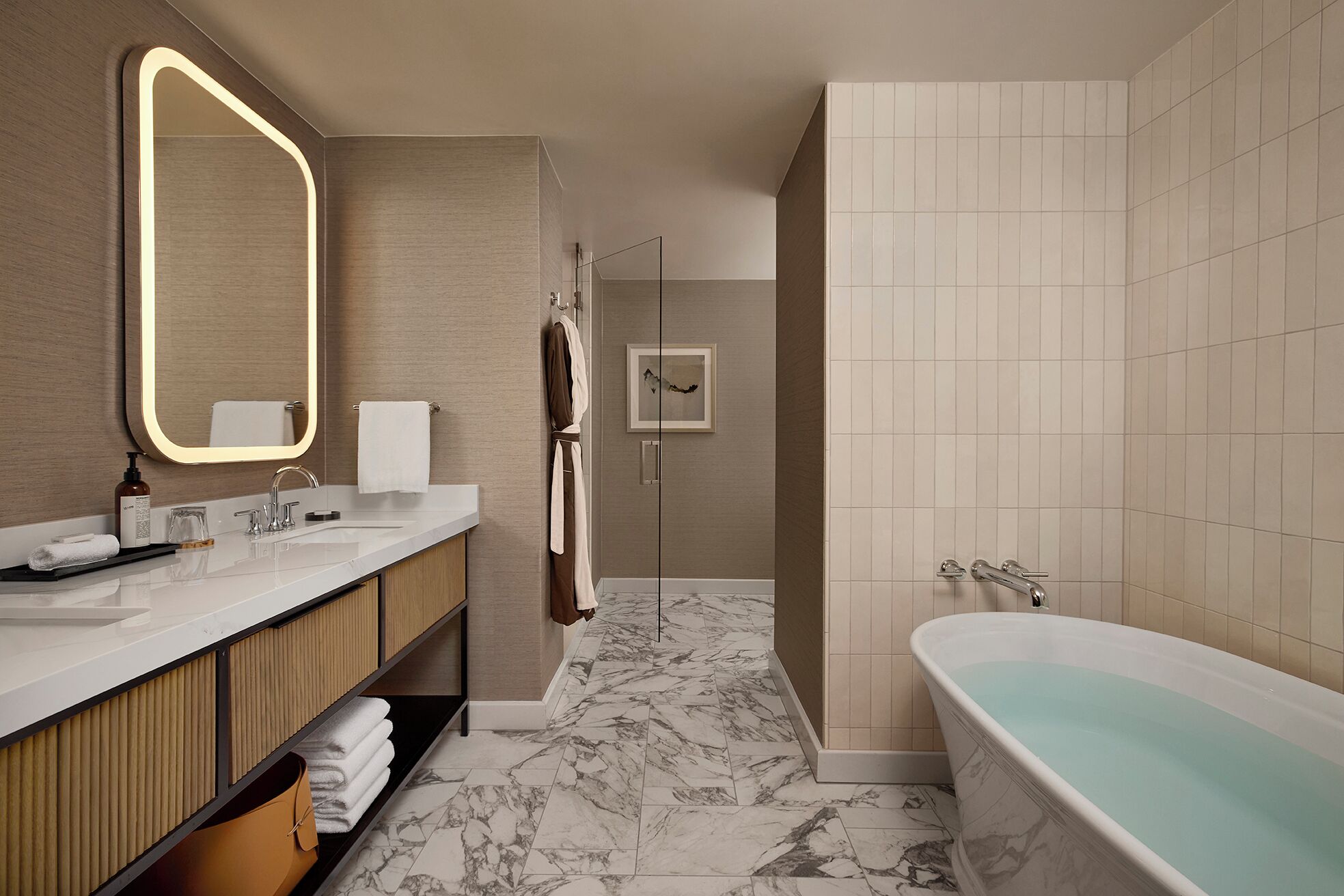 A modern bathroom with a marble floor, a freestanding bathtub, a vanity with a mirror, and a towel rack.
