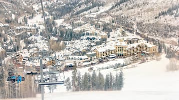 Un complejo turístico nevado con varios edificios, telesillas y montañas al fondo.