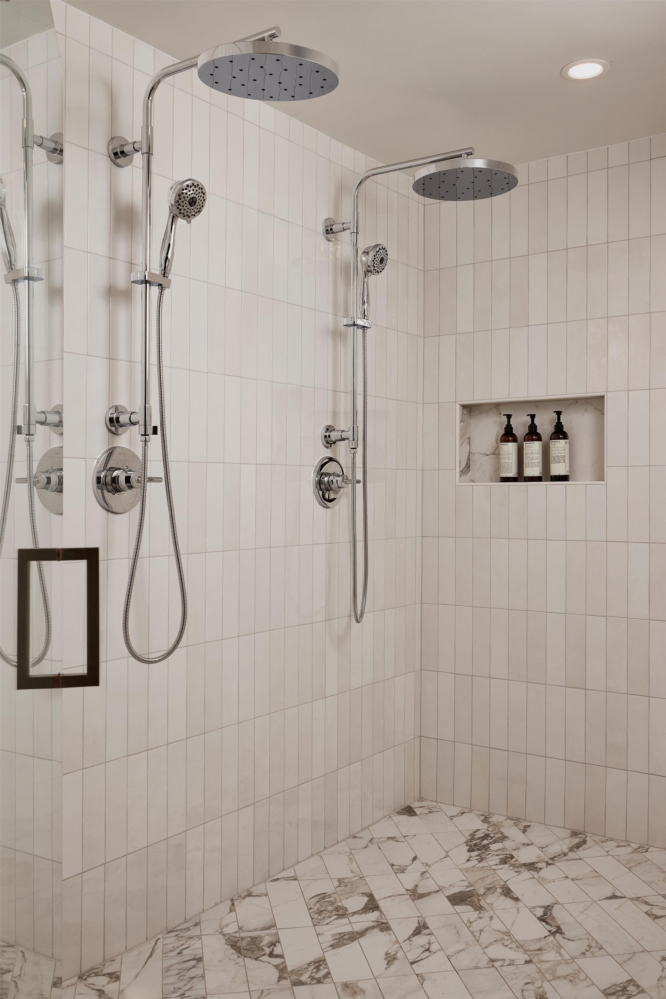 Een badkamer met een douche, een spiegel en een plank met flessen.
