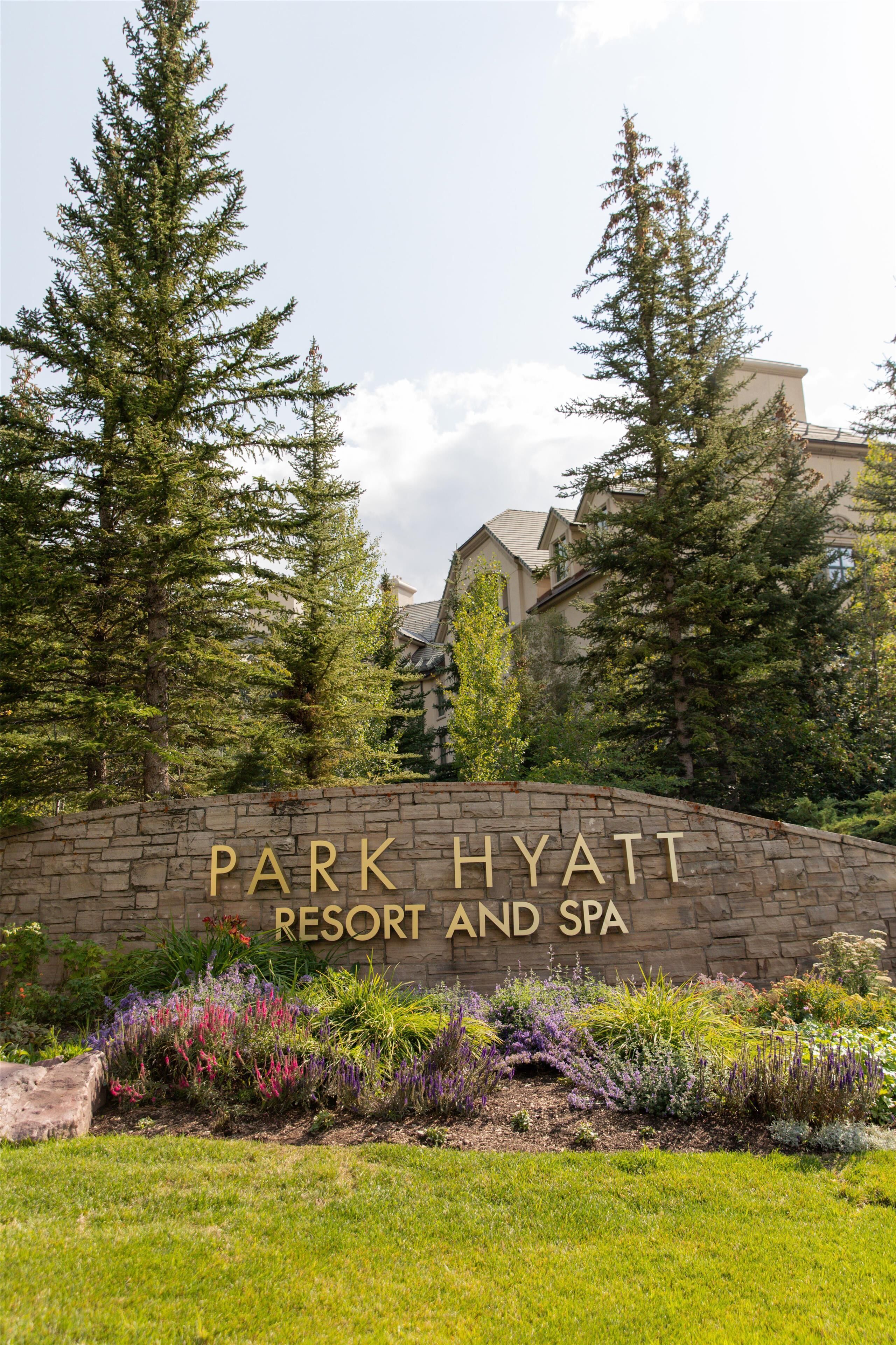 A stone wall with 'Park Hyatt Resort and Spa' written on it, surrounded by greenery and trees.