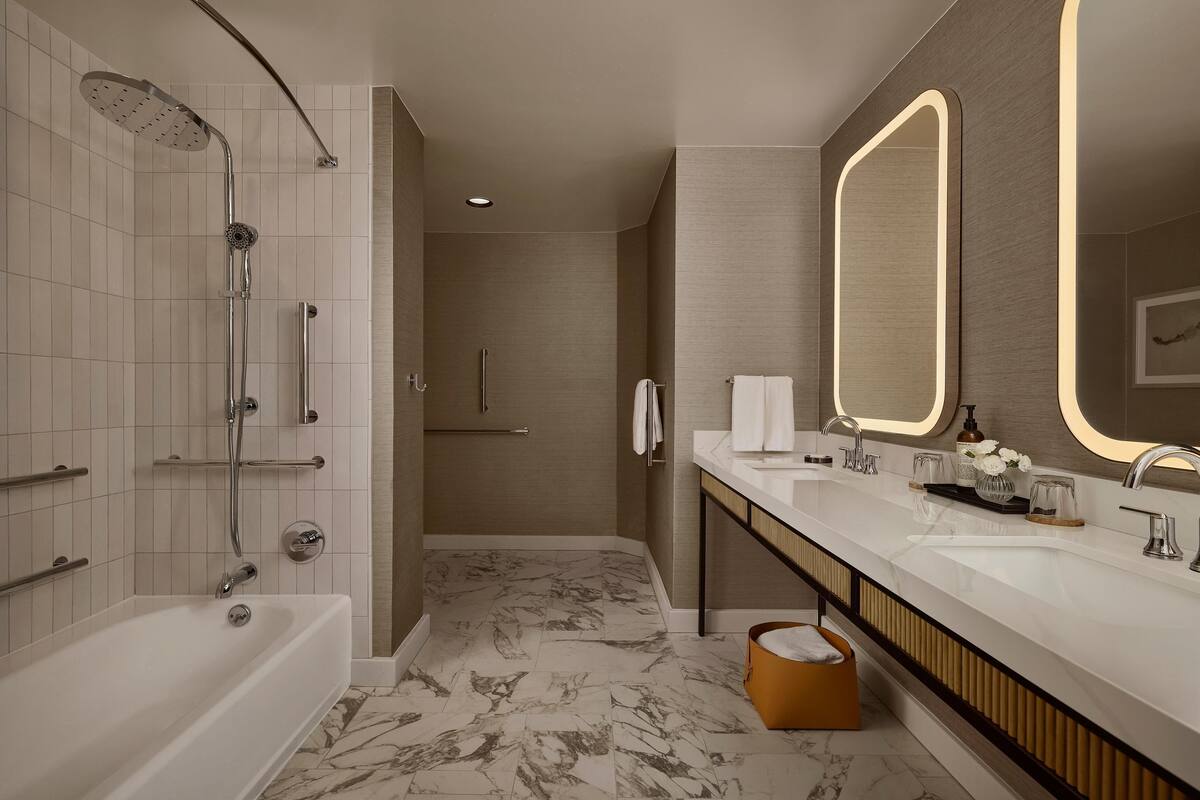 A modern bathroom with a bathtub, a shower, a vanity with a mirror, and a towel rack.