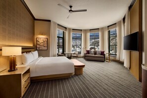 A hotel room with a bed, a desk, a chair, a sofa, a TV, and large windows with a view. - Park Hyatt Beaver Creek Resort and Spa (Avon)