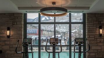 A gym with stationary bikes, treadmills, and a large window offering a view of mountains.