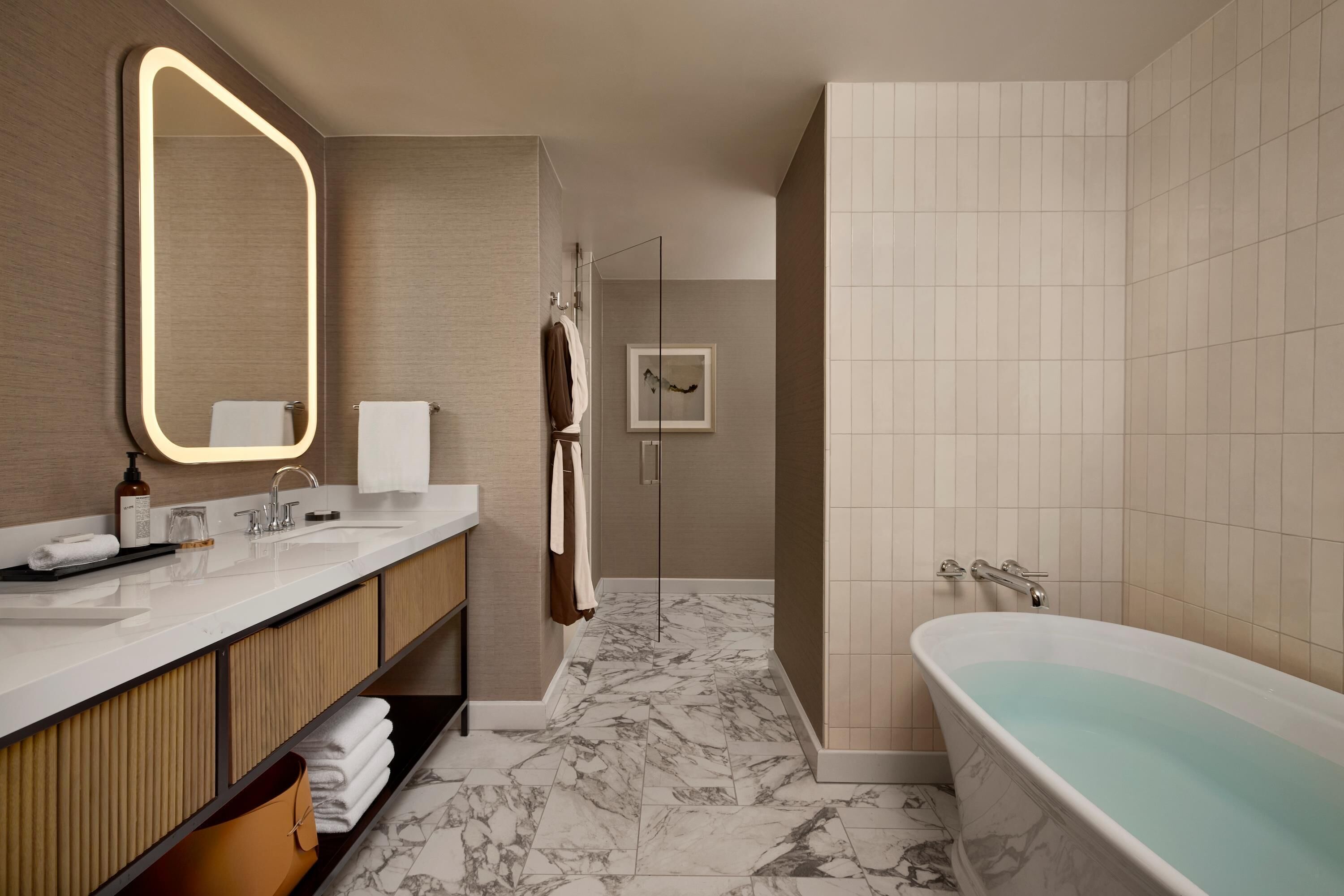 A modern bathroom with a large mirror, two sinks, a bathtub, and a shower.