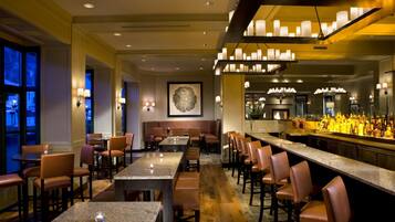 A bar area with seating, a counter with bottles, and a framed artwork on the wall.