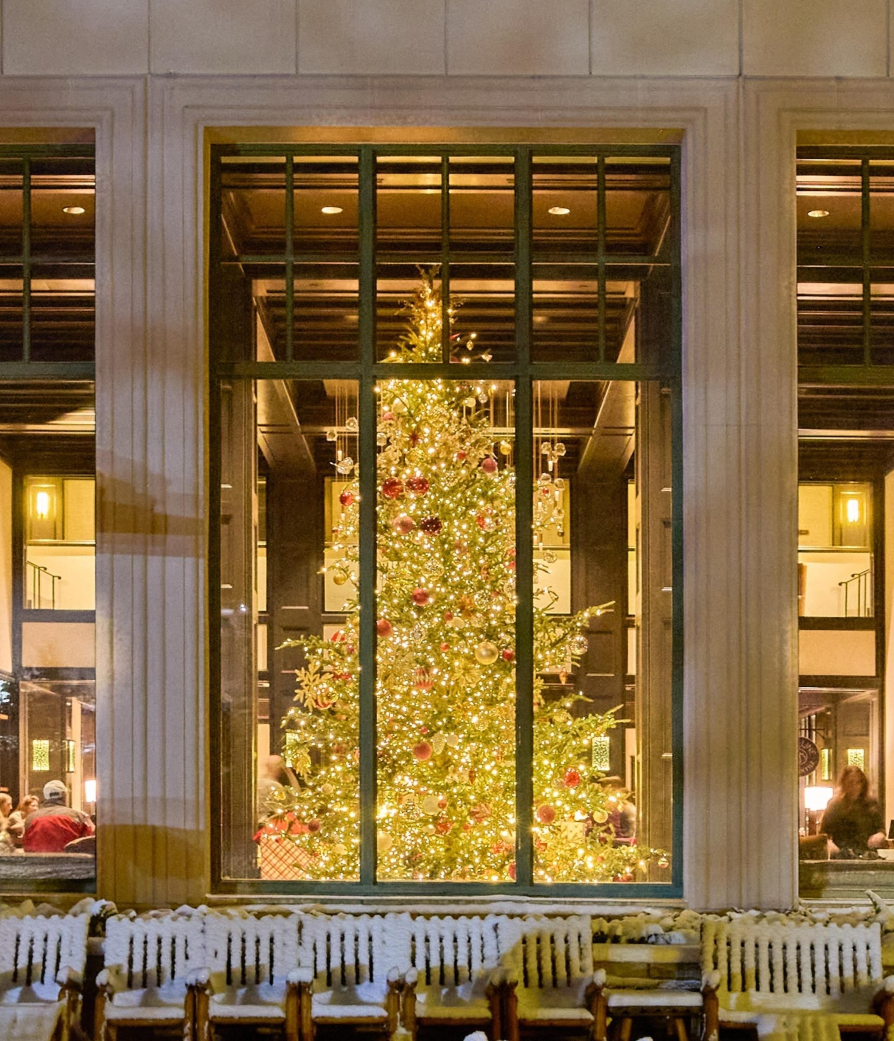 Ein großer, mit Schmuck und Lichtern geschmückter Weihnachtsbaum in der Hotelhalle.