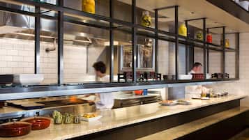 Una cocina moderna con electrodomésticos de acero inoxidable, repisas de vidrio con frascos, y encimera de granito.