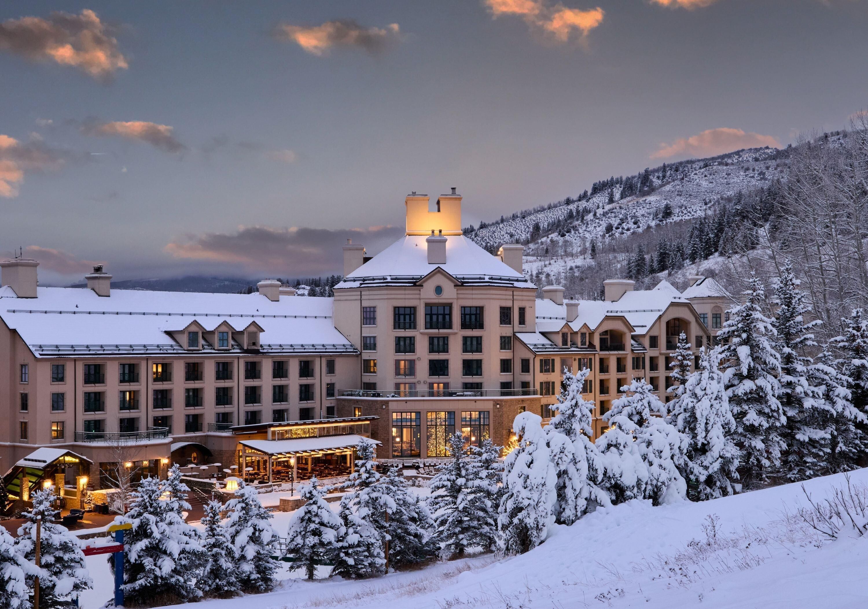 A large hotel with multiple buildings, a covered outdoor area, and snow-covered surroundings.
