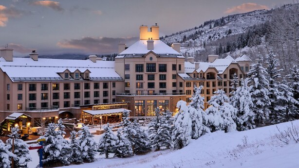 Un hotel grande con varias construcciones, un área exterior cubierta y alrededores nevados.