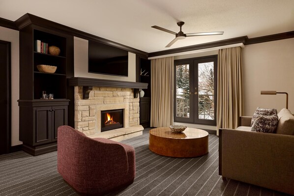 A living room with a fireplace, a ceiling fan, and a large window with curtains. - Park Hyatt Beaver Creek Resort and Spa (Avon)