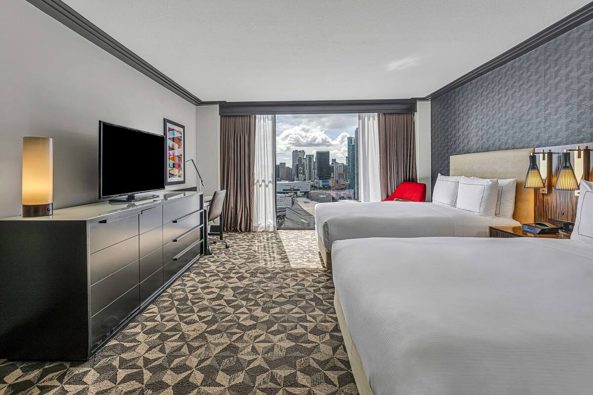 Une chambre d’hôtel avec un grand lit, une télévision, un bureau et une vue sur le panorama de la ville.