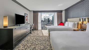 Een hotelkamer met een groot bed, een televisie, een bureau en uitzicht op de stadshemel.