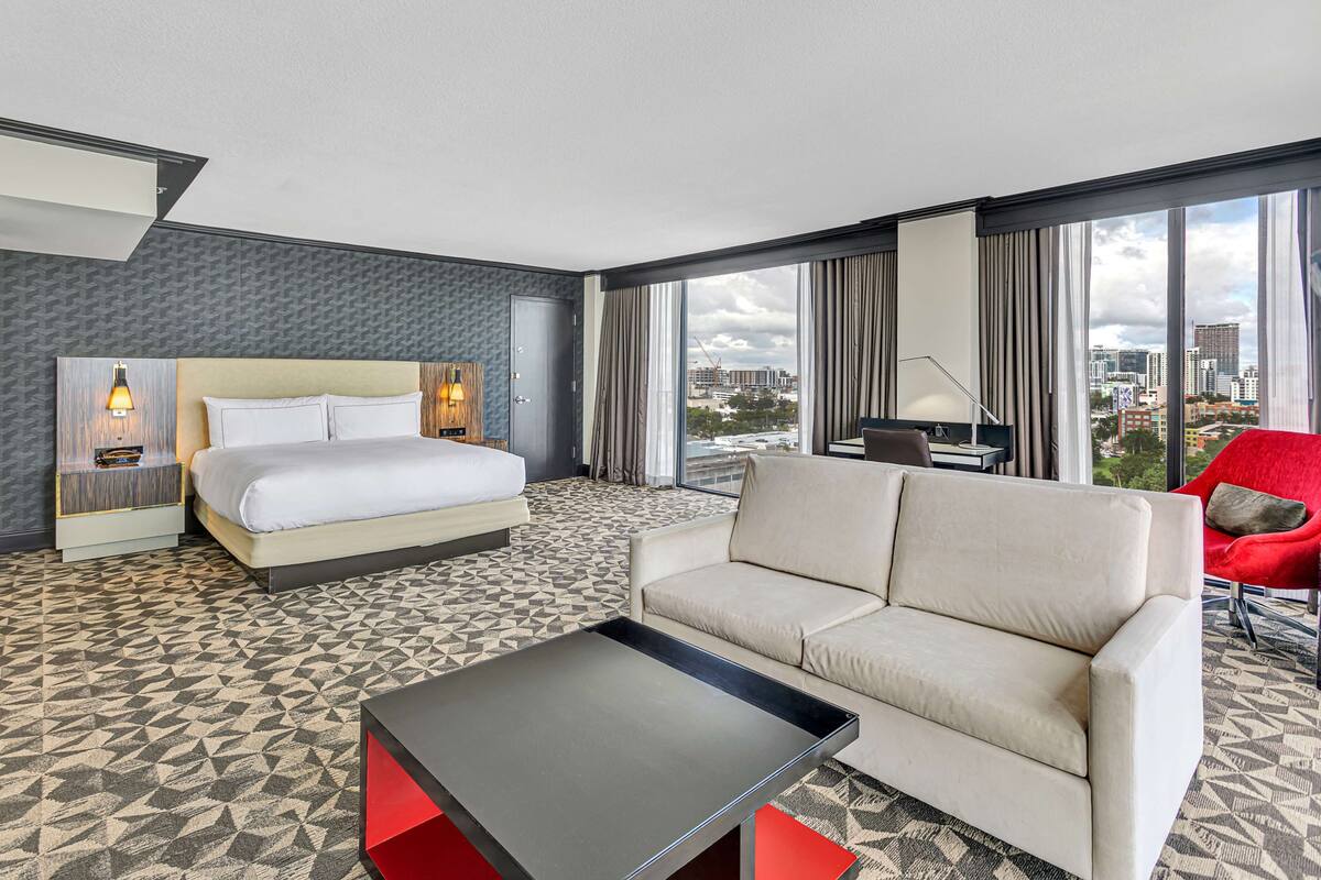 Une chambre d’hôtel avec un lit, un canapé, une table basse et une vue sur la ville.