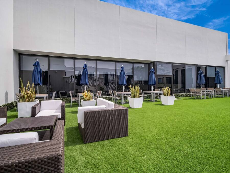 An outdoor patio with wicker furniture, potted plants, and umbrellas.