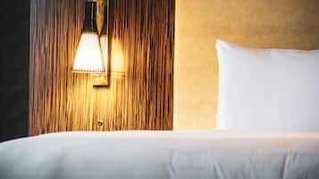 A neatly made bed with a white pillow and a wooden headboard with a wall-mounted light fixture.