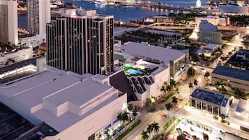 A high-rise hotel with a modern design, located near a waterfront with a view of the city skyline and a bridge.