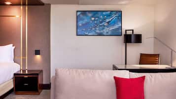 Une chambre d’hôtel moderne équipée d’un lit, d’un canapé, d’un bureau et d’un tableau au mur.