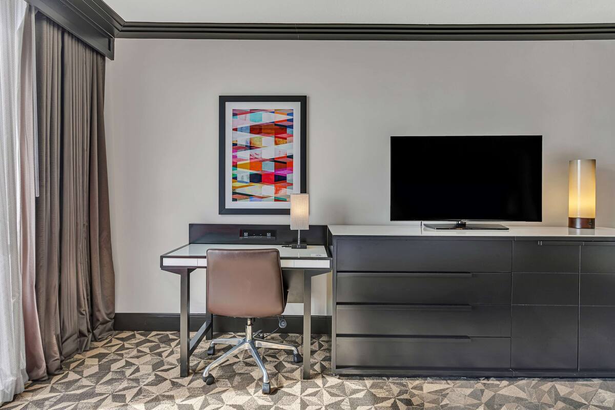 Une chambre d’hôtel équipée d’un bureau, d’une chaise, d’une télévision et d’un placard.