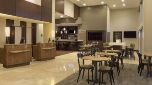 Un vestíbulo amplio con mostrador de recepción, zona de estar y bar.