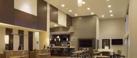 A spacious lobby with a reception desk, seating area, and a bar.