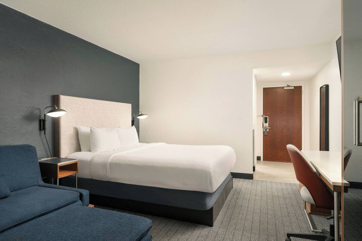 Quarto de hotel moderno com uma cama grande, uma mesa e uma cadeira.