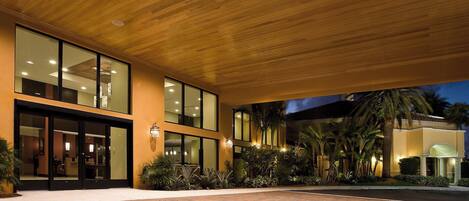 A modern building with large glass windows, a brick-paved courtyard, and a wooden ceiling.
