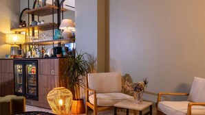 Un moderno vestíbulo de hotel con área de bar, asientos y una planta decorativa.