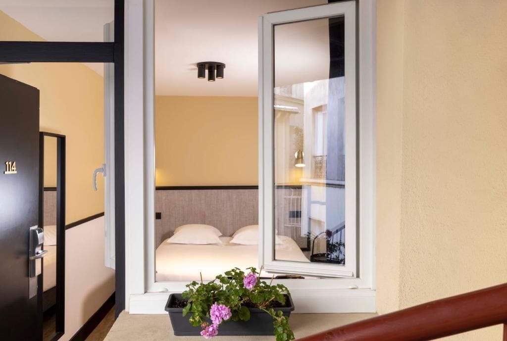 Una habitación de hotel con una cama, una ventana y una planta en maceta.