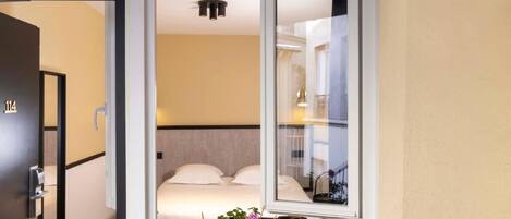 Una habitación de hotel con una cama, una ventana y una planta en maceta.