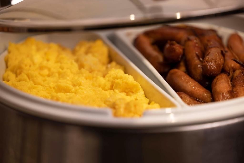 A buffet with yellow mashed potatoes and sausages.