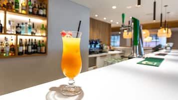 A bar area with a variety of liquor bottles and a cocktail glass with a straw and fruit garnish.