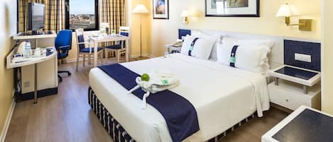Habitación de hotel con cama, escritorio, silla y vistas a la ciudad.