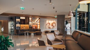 Eine moderne Lobby mit Sitzbereichen, einer Kaffeebar und einem großen, abstrakten Gemälde an der Wand.