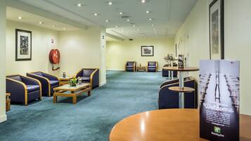 A hotel lobby with seating areas, a reception desk, and a fire extinguisher on the wall.