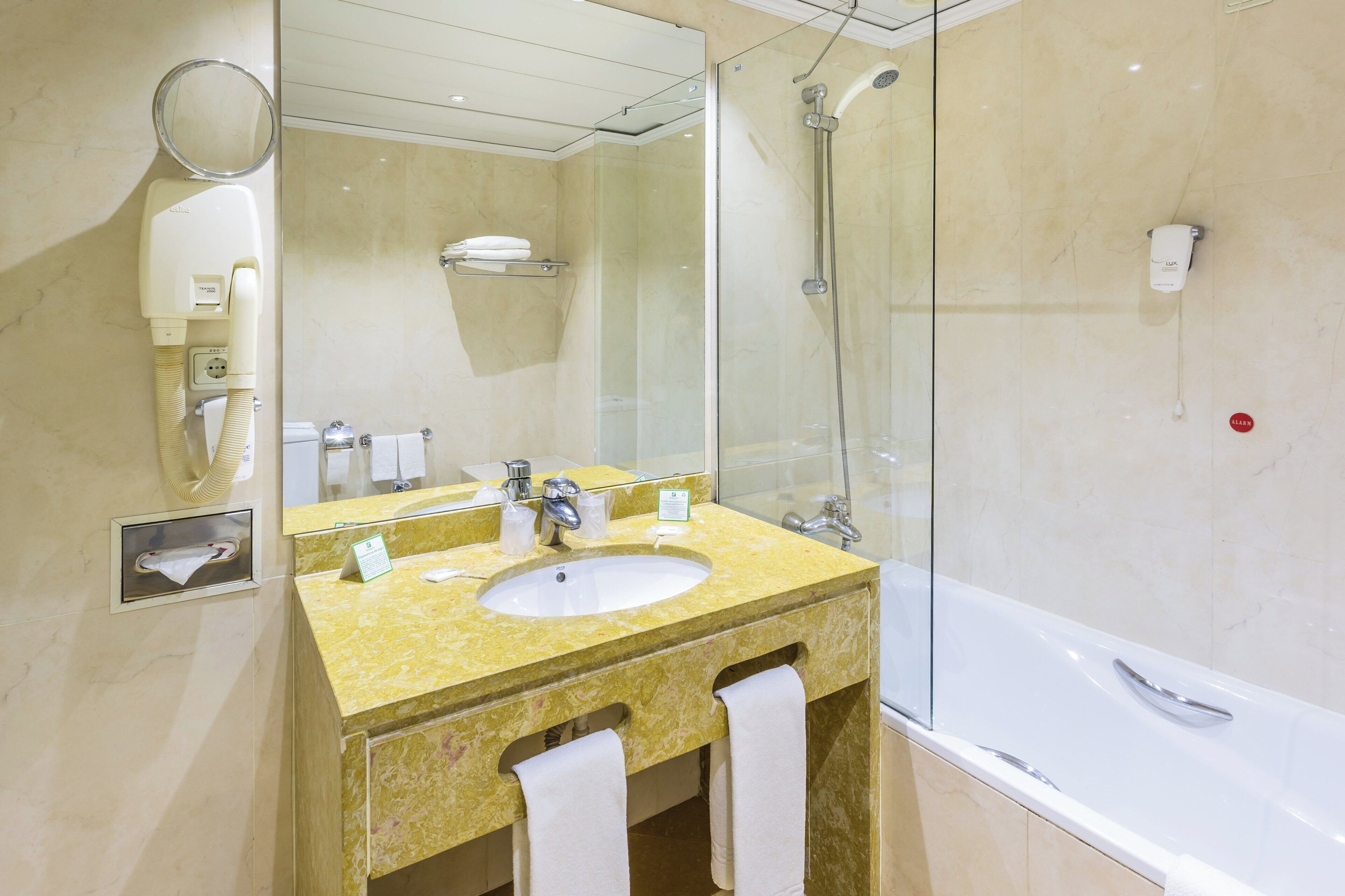 A bathroom with a sink, mirror, towel rack, and a glass-enclosed shower area.