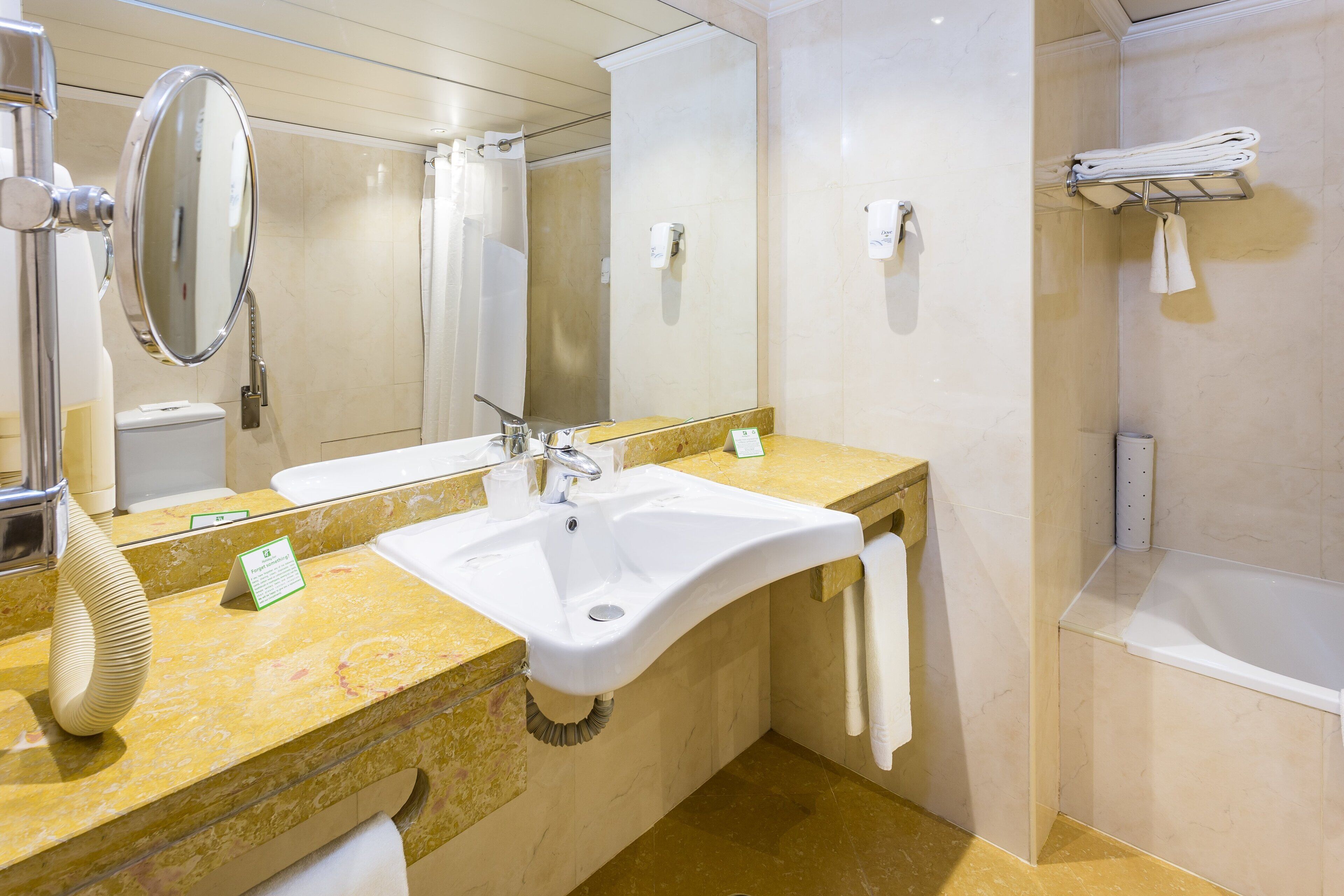 A modern bathroom with a sink, mirror, towel rack, and shower area.