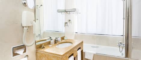 Un baño moderno con lavabo de mármol, un espejo grande, un cabezal de ducha de mano y una bañera.